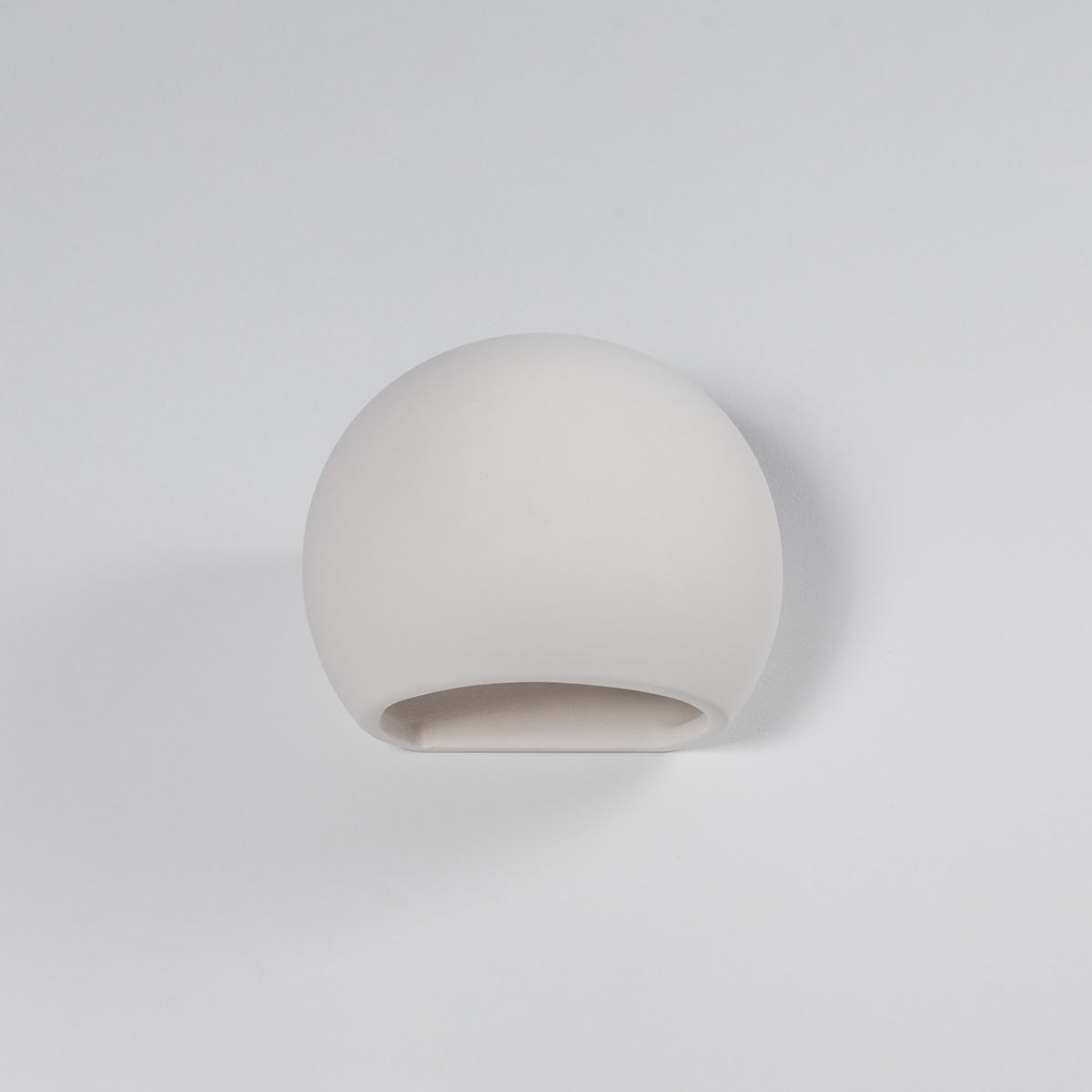Sollux Lighting modern ceramic wall lamp with a smooth, rounded white design mounted on a white wall
